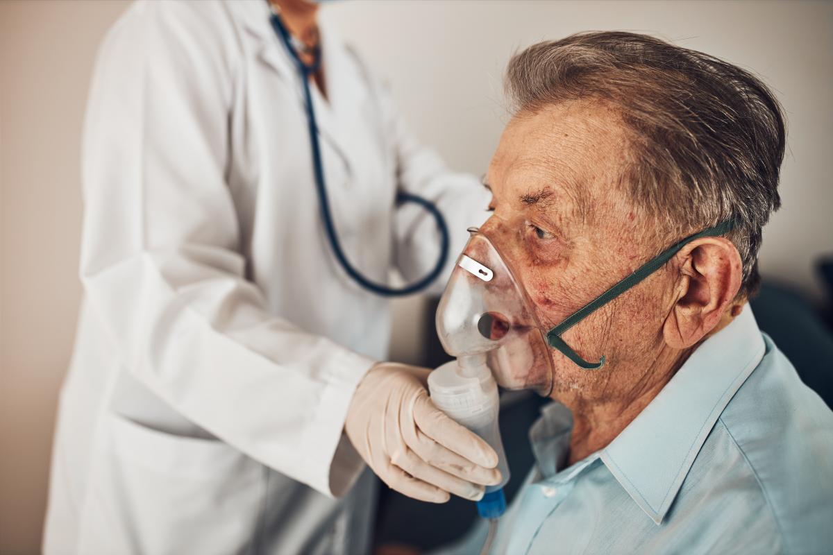 Dokter helpt oudere man met een inhalator